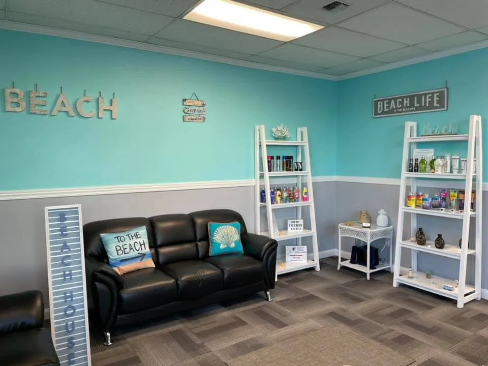 The waiting area, with a leather sofa, beach cushions and shelves of tanning lotions